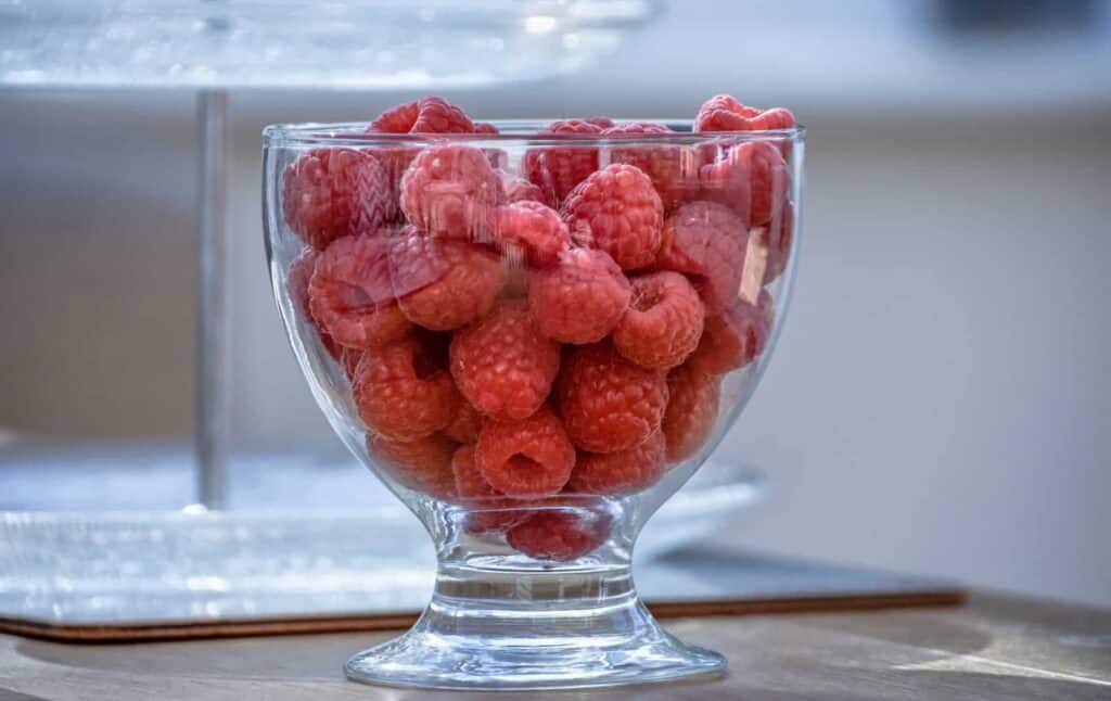red raspberries on clear glass jar