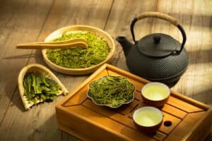 a tea set with a teapot and two cups of green tea